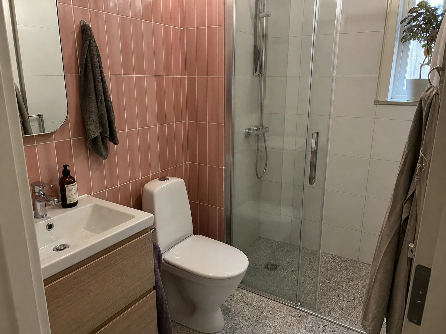 Färdigt badrum med dämpat rosa kakel och terrazzogolv