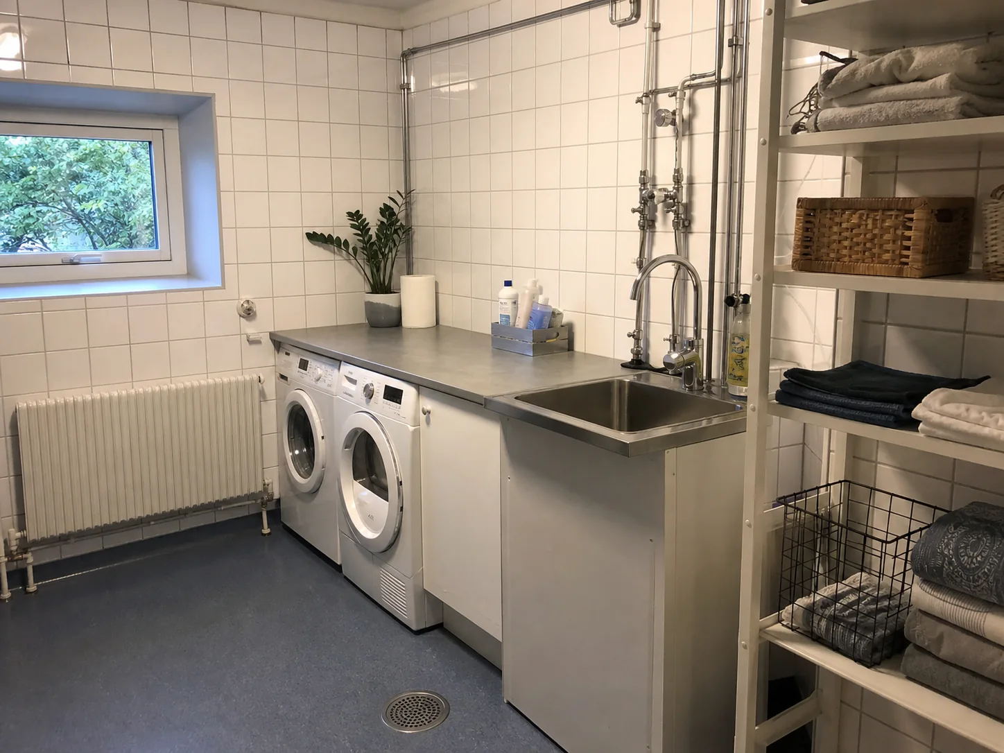 Praktisk tvättstuga i äldre villa med synliga rör och djup ho